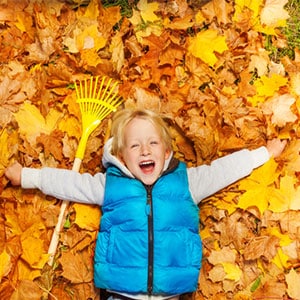 boy having fun raking fall leaves